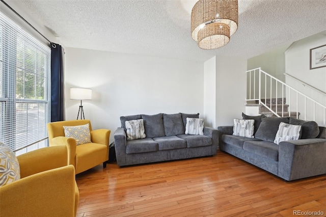 living room featuring hardwood / wood-style floors, a textured ceiling, and a notable chandelier