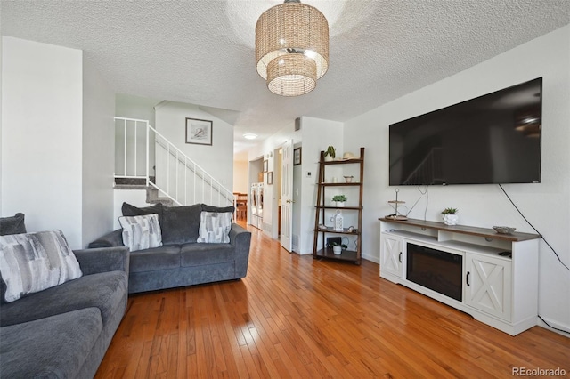 living room with hardwood / wood-style flooring, an inviting chandelier, and a textured ceiling