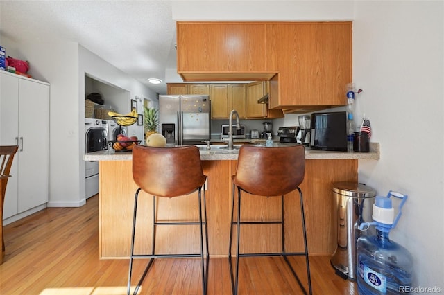 kitchen featuring light hardwood / wood-style flooring, independent washer and dryer, stainless steel fridge, and kitchen peninsula