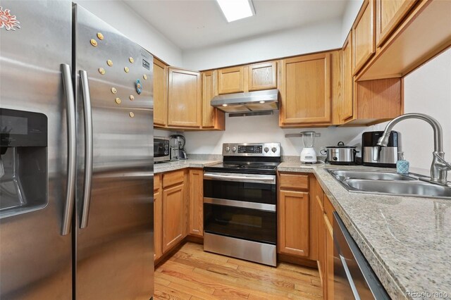 kitchen featuring light stone counters, appliances with stainless steel finishes, sink, and light hardwood / wood-style flooring