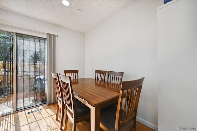 dining area featuring light hardwood / wood-style floors and a textured ceiling