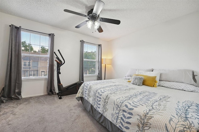 carpeted bedroom featuring ceiling fan and a textured ceiling