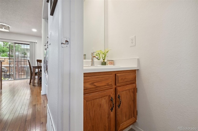 bathroom with wood-type flooring, vanity, and a textured ceiling