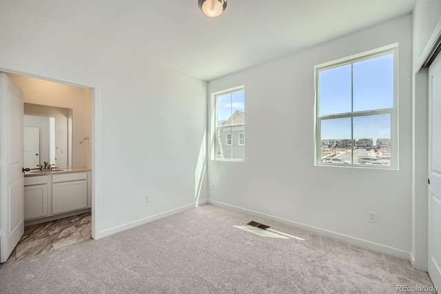 708 N Bently St, Watkins, CO 80137 - unfurnished bedroom with light colored carpet, baseboards, a sink, and ensuite bathroom