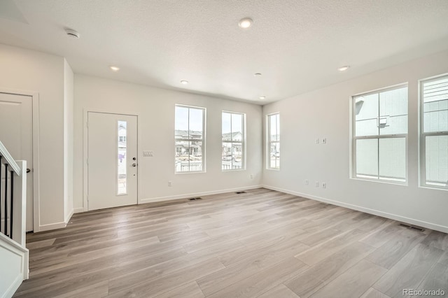 708 N Bently St, Watkins, CO 80137 - entryway with healthy amount of natural light, light wood-type flooring, recessed lighting, baseboards, and a textured ceiling