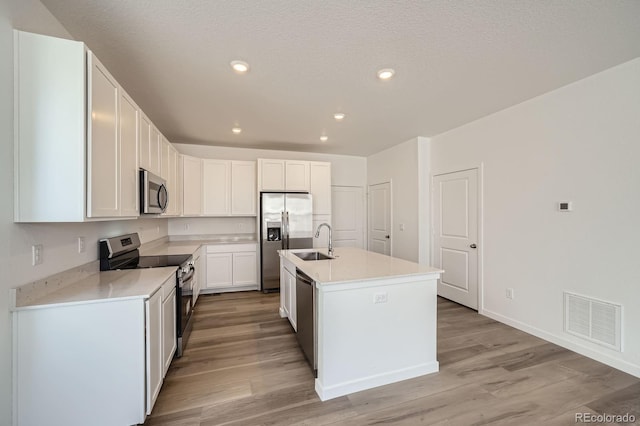 708 N Bently St, Watkins, CO 80137 - kitchen with stainless steel appliances, a sink, light wood-style floors, light countertops, and white cabinets