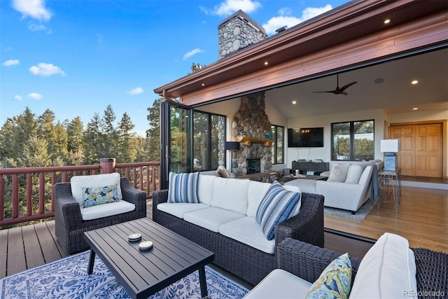 deck featuring a ceiling fan and an outdoor living space with a fireplace