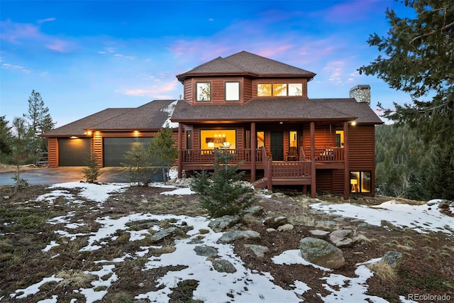 view of front of house featuring a garage, covered porch, a chimney, and log veneer siding