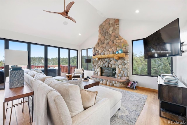 living area featuring ceiling fan, high vaulted ceiling, recessed lighting, a fireplace, and light wood finished floors