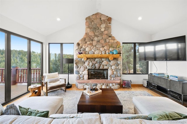 living room featuring recessed lighting, light wood-style flooring, high vaulted ceiling, and a stone fireplace