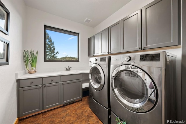 laundry area with separate washer and dryer, a sink, visible vents, cabinet space, and stone finish flooring