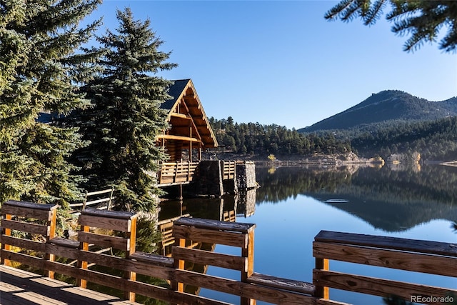 view of dock with a forest view and a water and mountain view