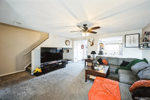 carpeted living room featuring visible vents, stairs, and a ceiling fan