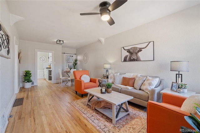 living room with light hardwood / wood-style flooring and ceiling fan