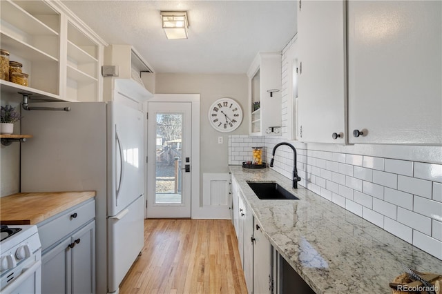 kitchen with light stone countertops, white cabinetry, and sink