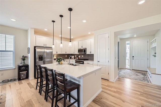 515 176th Ave, Broomfield, CO 80023 - kitchen with appliances with stainless steel finishes, a sink, light wood finished floors, a kitchen bar, and white cabinets
