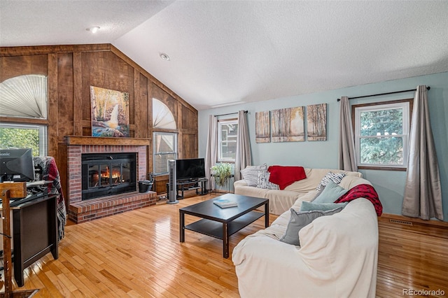 16724 E Hialeah Ave, Centennial, CO 80015 - living area featuring vaulted ceiling, a textured ceiling, plenty of natural light, a fireplace, and wooden walls