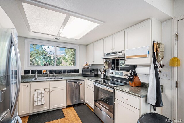 16724 E Hialeah Ave, Centennial, CO 80015 - kitchen featuring stainless steel appliances, under cabinet range hood, light wood-style flooring, white cabinets, and dark countertops