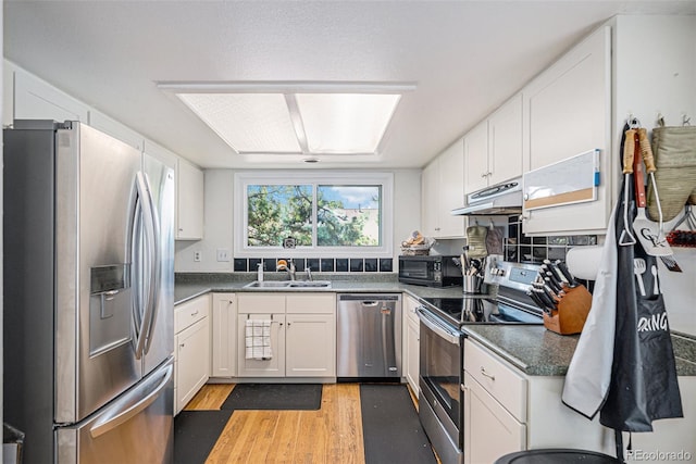 16724 E Hialeah Ave, Centennial, CO 80015 - kitchen featuring appliances with stainless steel finishes, under cabinet range hood, light wood-style flooring, and white cabinetry
