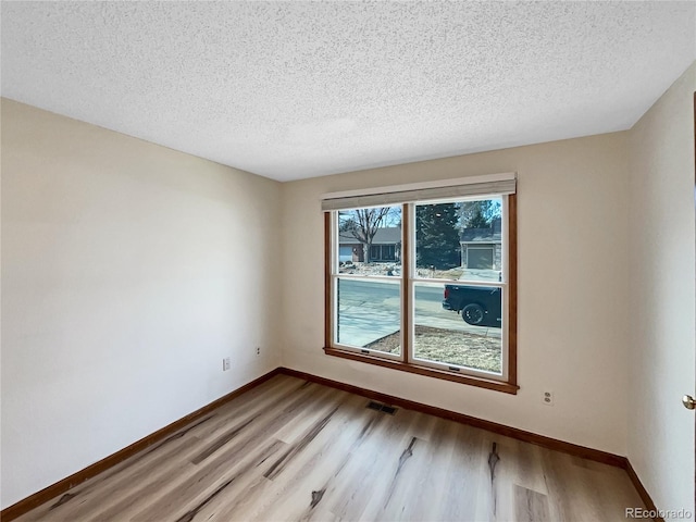 unfurnished room with light hardwood / wood-style flooring and a textured ceiling