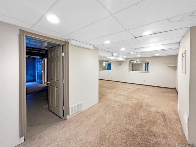 basement featuring a paneled ceiling and light carpet