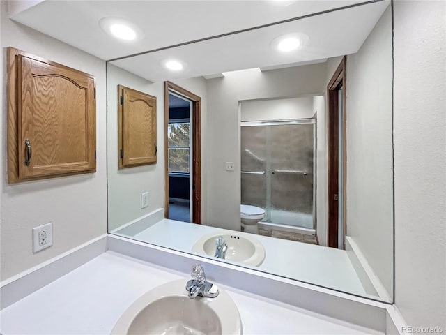 bathroom featuring vanity, toilet, and a shower with door