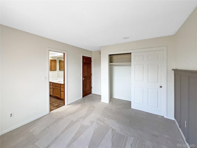 unfurnished bedroom featuring ensuite bath, light carpet, and a closet