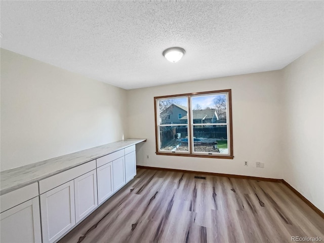 empty room featuring a textured ceiling and light hardwood / wood-style flooring