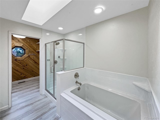 bathroom with a skylight, separate shower and tub, hardwood / wood-style flooring, and wooden walls