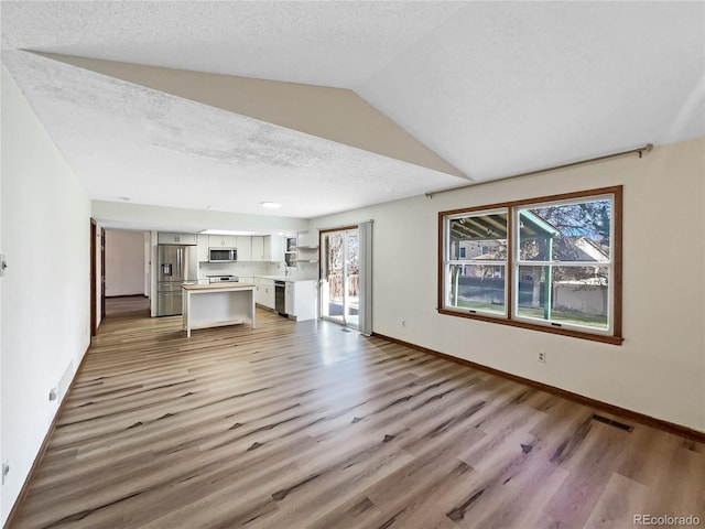 unfurnished living room with a textured ceiling, light wood-type flooring, and sink