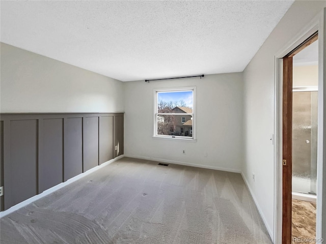 empty room featuring a textured ceiling and light colored carpet