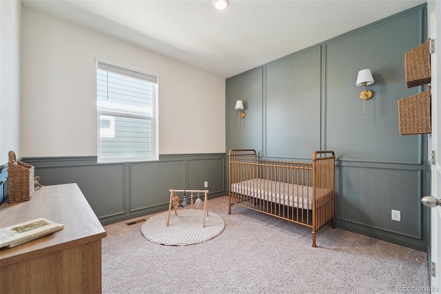 2226 Monte Vista St, Fort Lupton, CO 80621 - carpeted bedroom featuring a nursery area, visible vents, wainscoting, and a decorative wall