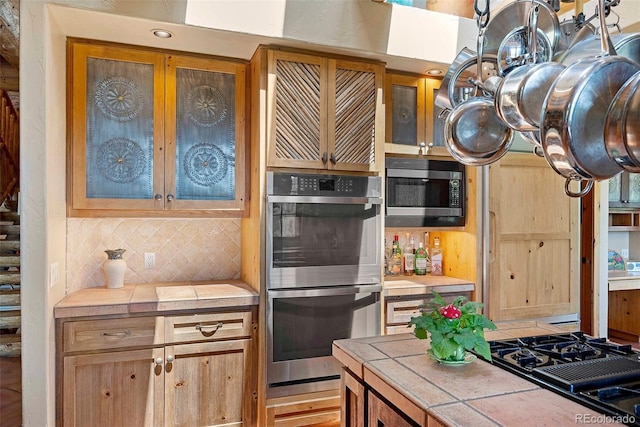 28267 Meadowlark Dr, Golden, CO 80401 - kitchen with appliances with stainless steel finishes, tile counters, backsplash, and glass insert cabinets