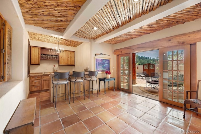 28267 Meadowlark Dr, Golden, CO 80401 - kitchen with beamed ceiling, brown cabinetry, french doors, a breakfast bar, and a chandelier