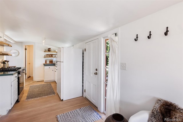 426 Corona Ave, Palmer Lake, CO 80133 - kitchen featuring freestanding refrigerator, gas stove, open shelves, light wood-type flooring, and dark countertops