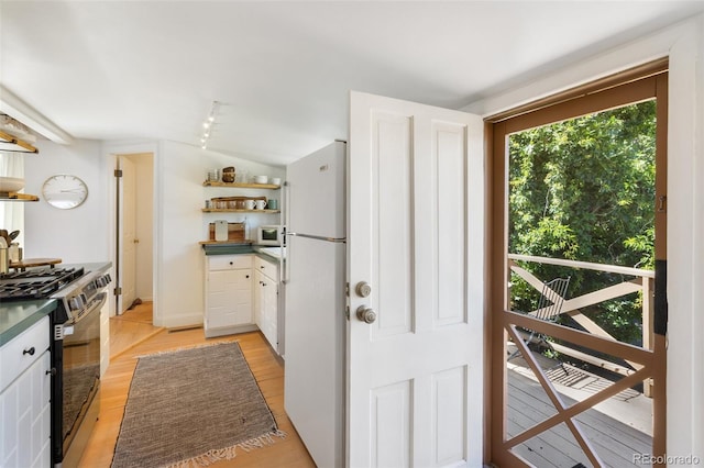 426 Corona Ave, Palmer Lake, CO 80133 - kitchen with open shelves, white appliances, dark countertops, white cabinets, and light wood-type flooring