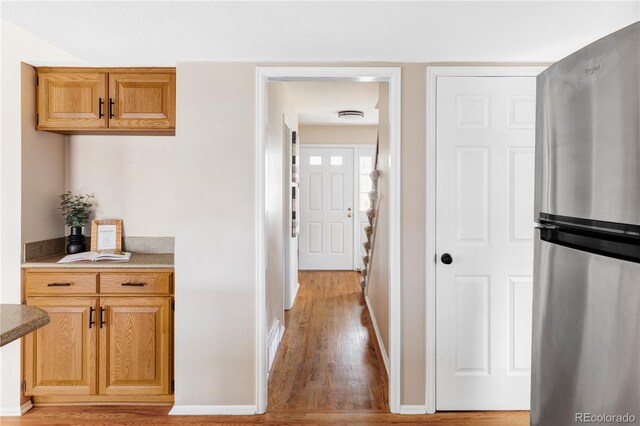 hall featuring light wood-type flooring and baseboards