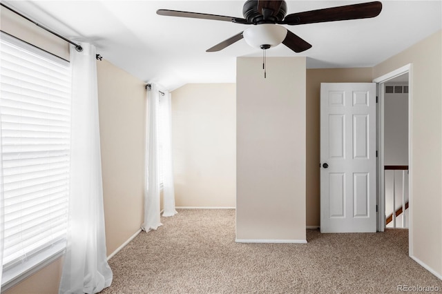 empty room featuring a healthy amount of sunlight, baseboards, lofted ceiling, and carpet