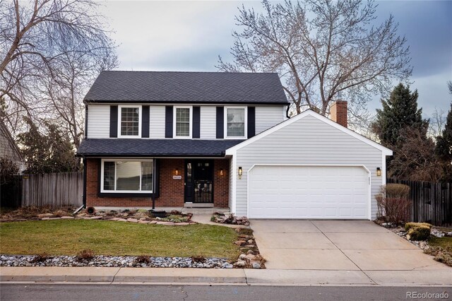 traditional-style house with brick siding, a front lawn, fence, concrete driveway, and a garage