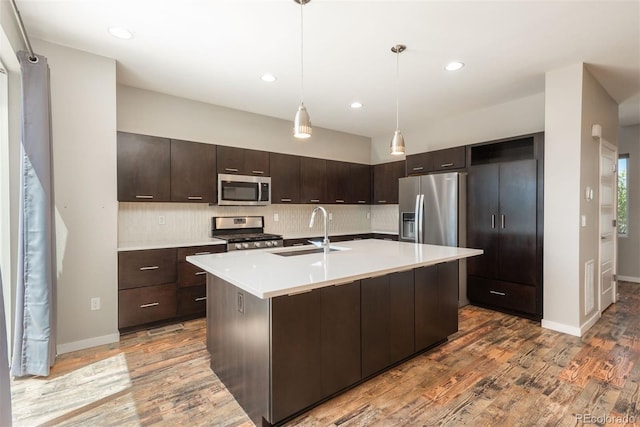9781 Dunning Cir, Highlands Ranch, CO 80129 - kitchen with appliances with stainless steel finishes, dark brown cabinets, light wood finished floors, tasteful backsplash, and recessed lighting