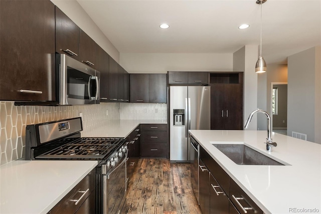 9781 Dunning Cir, Highlands Ranch, CO 80129 - kitchen with appliances with stainless steel finishes, light countertops, dark wood-style floors, dark brown cabinetry, and decorative light fixtures