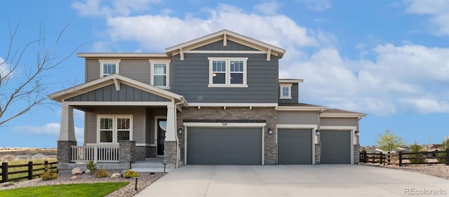 craftsman inspired home with a porch, fence, driveway, and stone siding