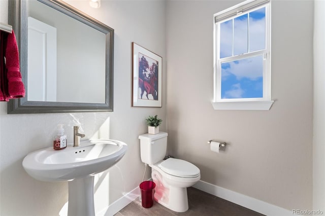bathroom with toilet, baseboards, and wood finished floors