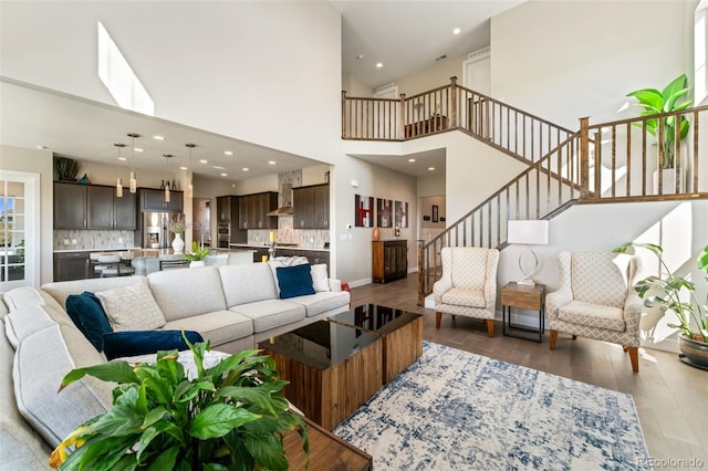 living room featuring a high ceiling, recessed lighting, baseboards, wood finished floors, and stairway