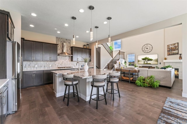 kitchen with open floor plan, dark wood-style floors, recessed lighting, wall chimney exhaust hood, and a sink