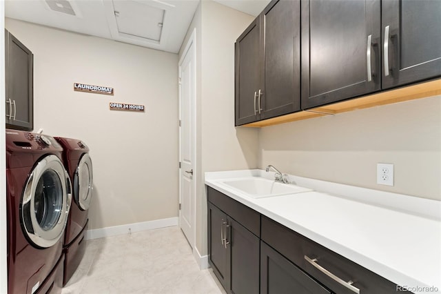 laundry room with cabinet space, washing machine and clothes dryer, a sink, attic access, and baseboards