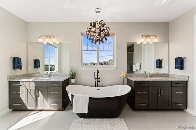 bathroom with an inviting chandelier, a sink, tile patterned flooring, two vanities, and a soaking tub