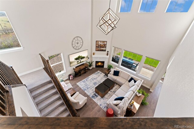 3128 Bivouac Pt, Castle Rock, CO 80108 - living room featuring baseboards, a lit fireplace, wood finished floors, and a towering ceiling