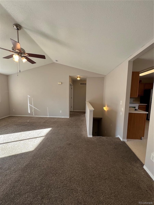 carpeted spare room with a textured ceiling, ceiling fan, and vaulted ceiling