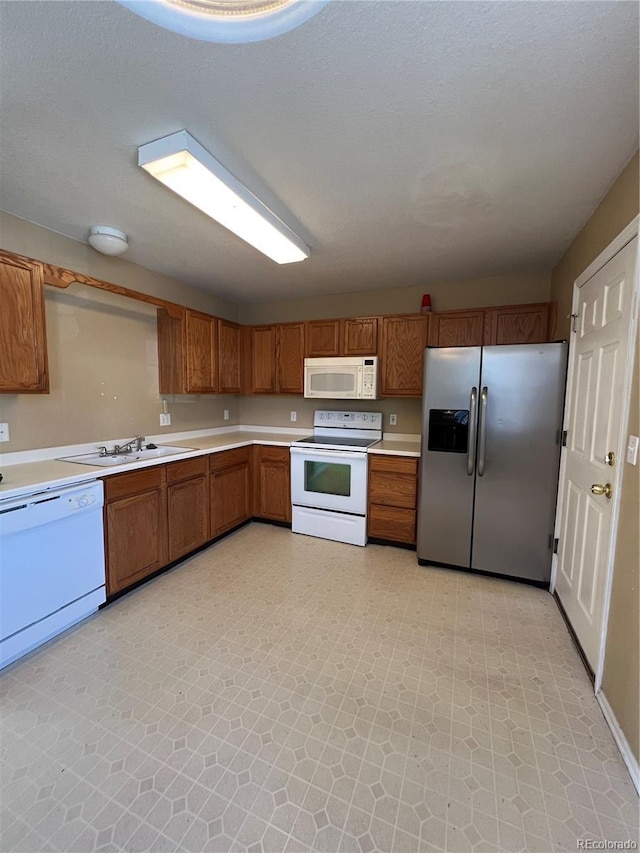 kitchen with sink, white appliances, and a textured ceiling